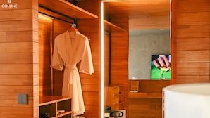 A wooden interior with a robe hanging, a television, and a wooden cabinet. - Colline Dalat (Xuan Huong - Da Lat)
