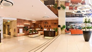 A modern hotel lobby with a reception desk, seating area, and decorative plants. - Colline Dalat (Xuan Huong - Da Lat)