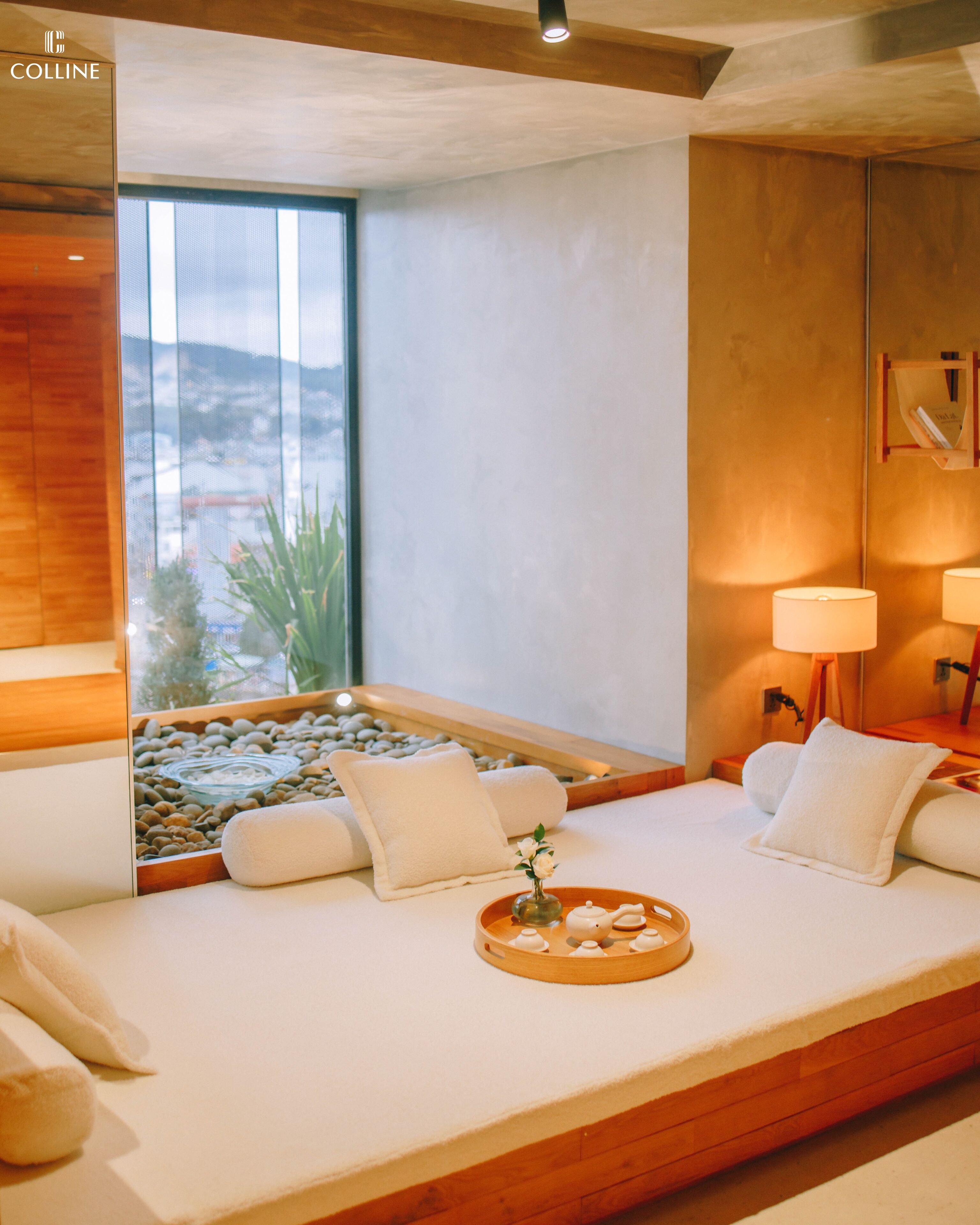 Uma sala de spa com uma grande janela, um pequeno elemento de água e duas luminárias.
