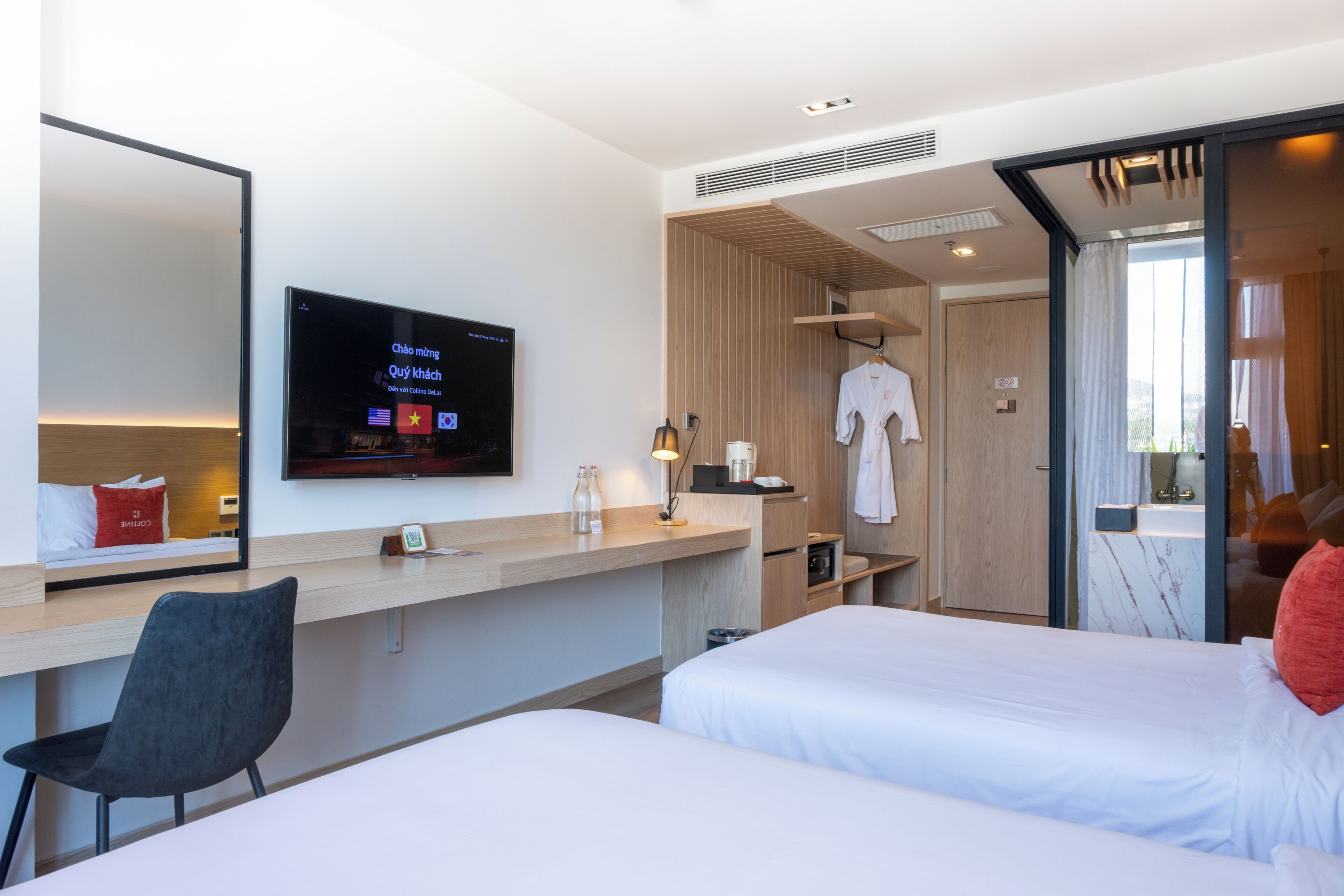 Een hotelkamer met een bed, een bureau, een stoel, een televisie en een spiegel.