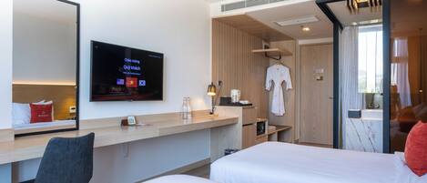 Een hotelkamer met een bed, een bureau, een stoel, een televisie en een spiegel.