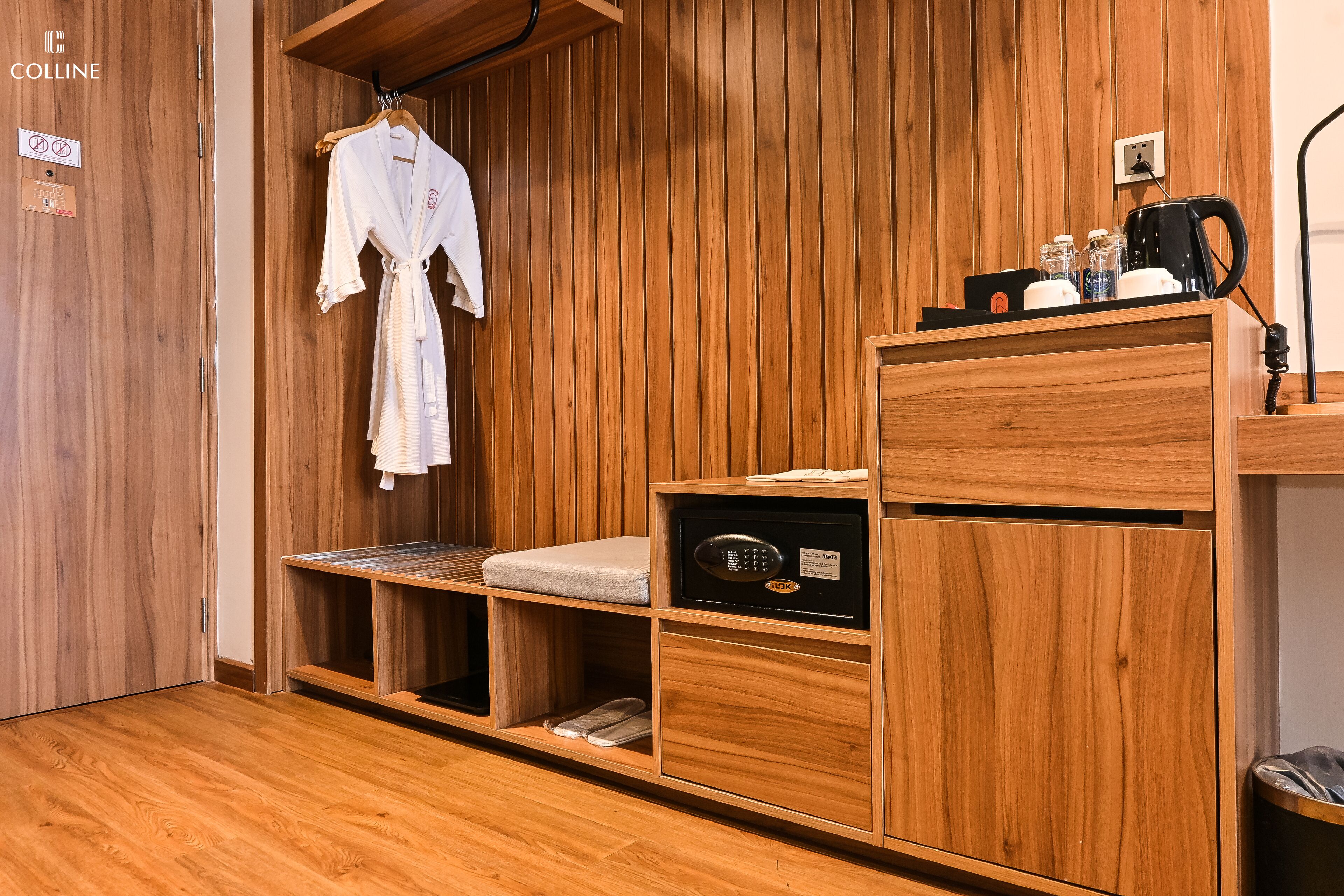 A wooden-paneled room with a robe hanging, a massage table, a massage chair, and a coffee station.