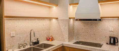 A modern kitchen with granite countertops, wooden cabinets, a stainless steel sink, and a range hood.