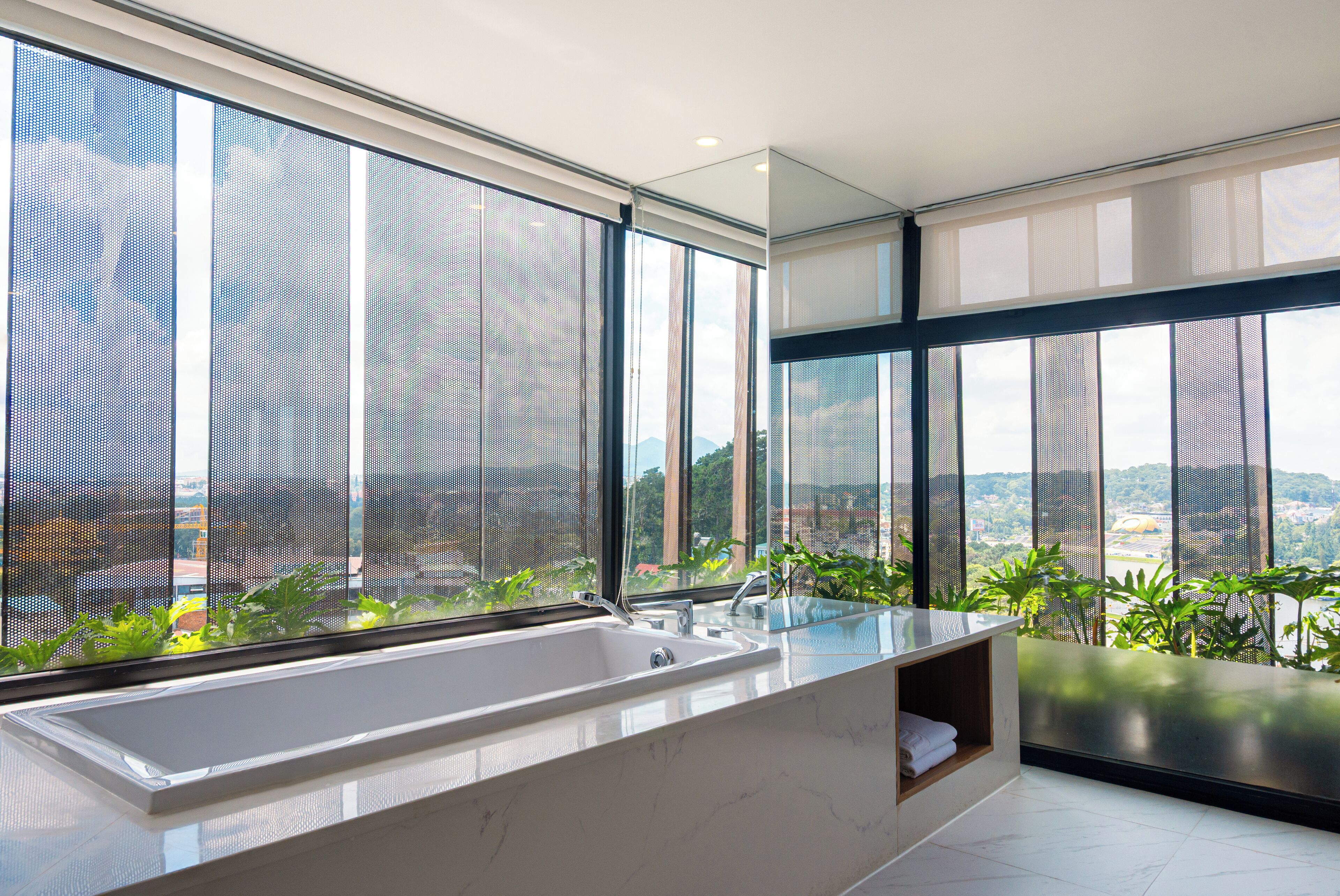 A modern bathroom with a large bathtub, a sink, and a window overlooking a cityscape.