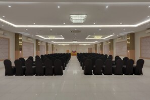 A conference room with rows of chairs, a podium, and a chandelier.