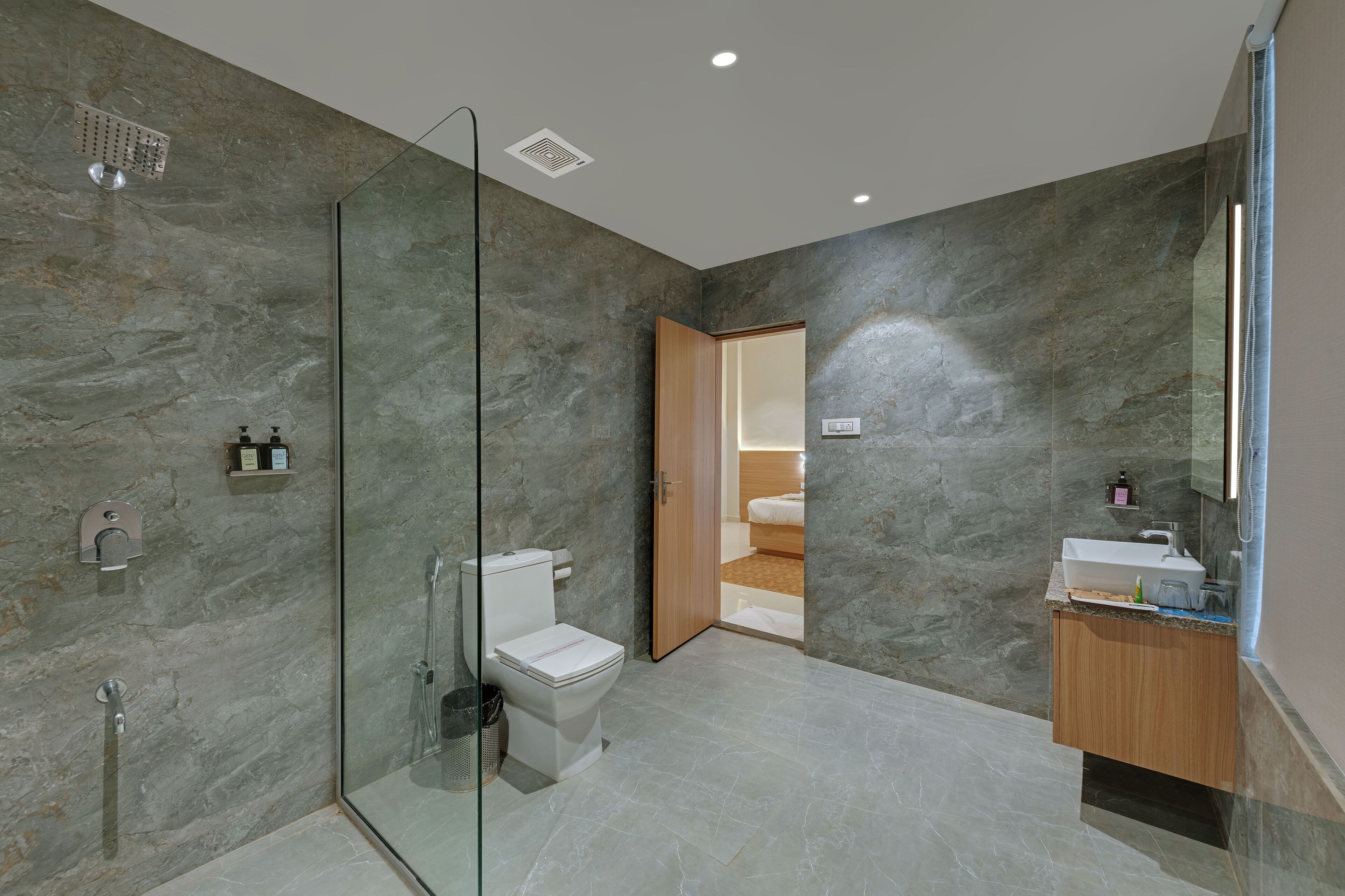 A modern bathroom with a glass-enclosed shower, a toilet, and a sink.