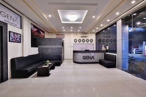 Welcome to GENA, where guests can check in and relax in the stylish reception area featuring a comfortable seating area and a large television.