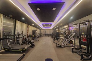 Une salle de sport équipée de tapis de course, d’appareils de musculation et de poids libres.