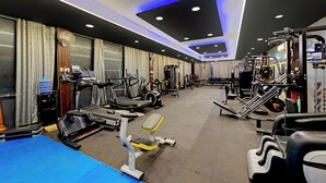 Une salle de sport équipée de tapis de course, d’appareils de musculation et de poids libres.