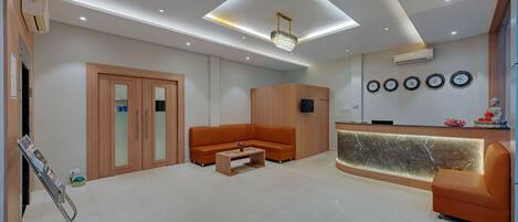 A modern reception area with a wooden reception desk, a sofa, and a coffee table.