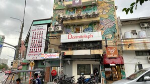 A multi-story building with a colorful floral mural, a sign for 'Dormitsph UST', and several parked motorcycles. - Dormitelsph UST (Manila)