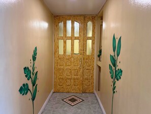 A hallway with a wooden door featuring multiple windows and a decorative pattern. - Dormitelsph UST (Manila)