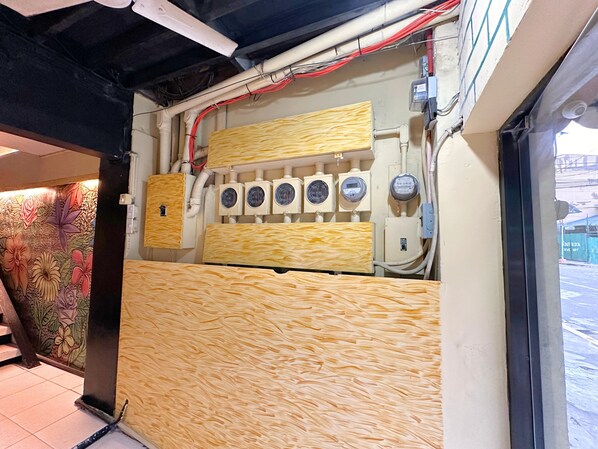 Una stanza con pavimento piastrellato, parete decorata con motivi floreali e pannello di legno con prese elettriche e interruttori.