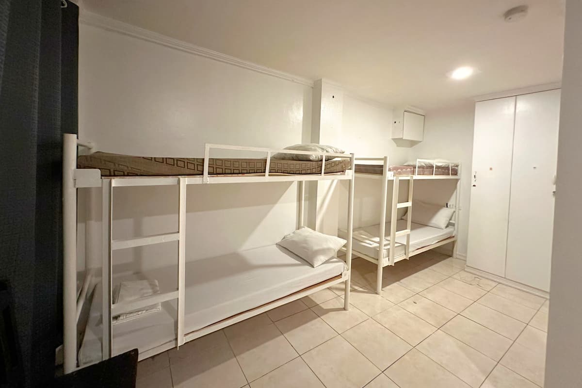 A room with bunk beds, a wardrobe, and a small cabinet.