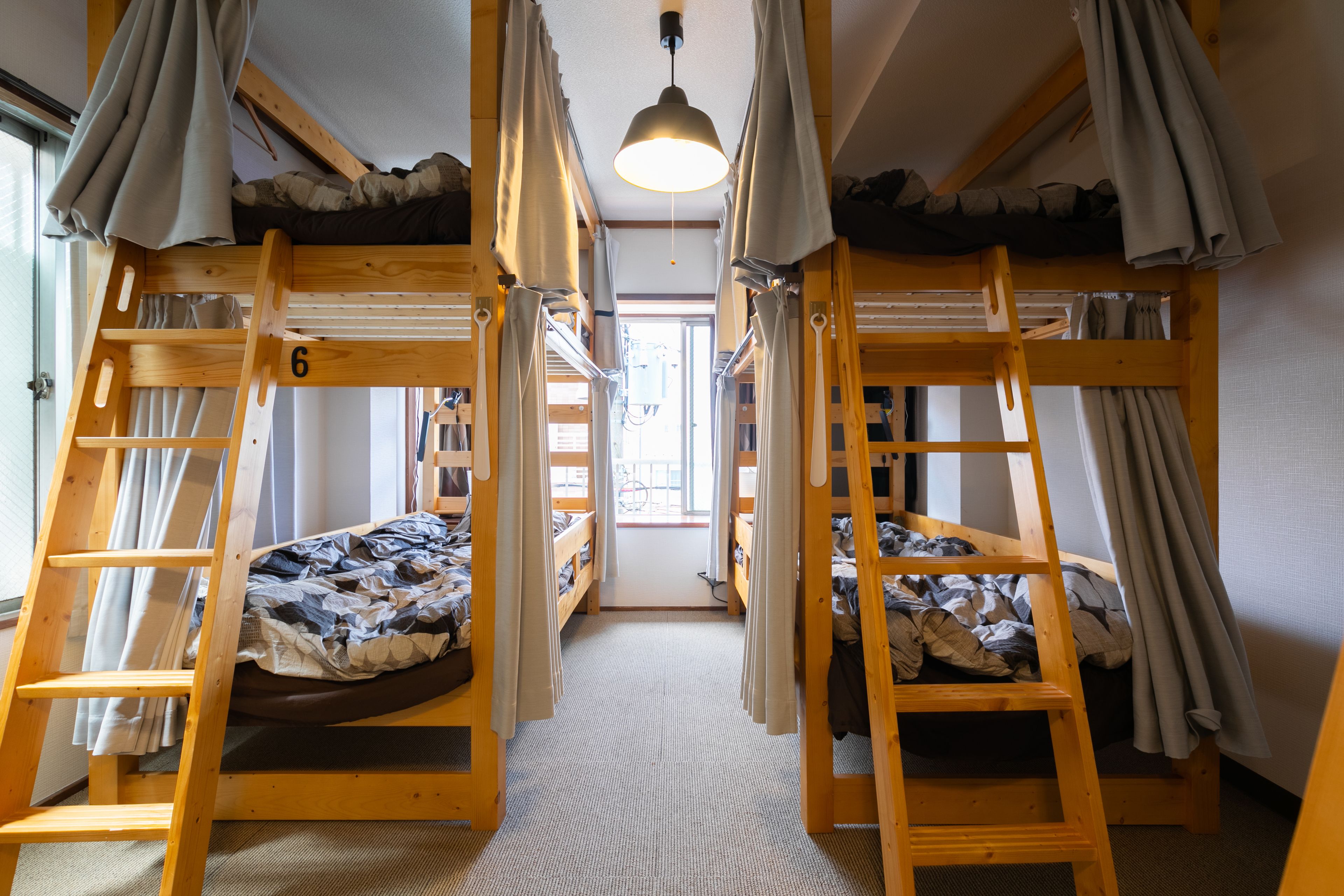 A bunk bed room with wooden bunk beds, a ladder, and curtains.