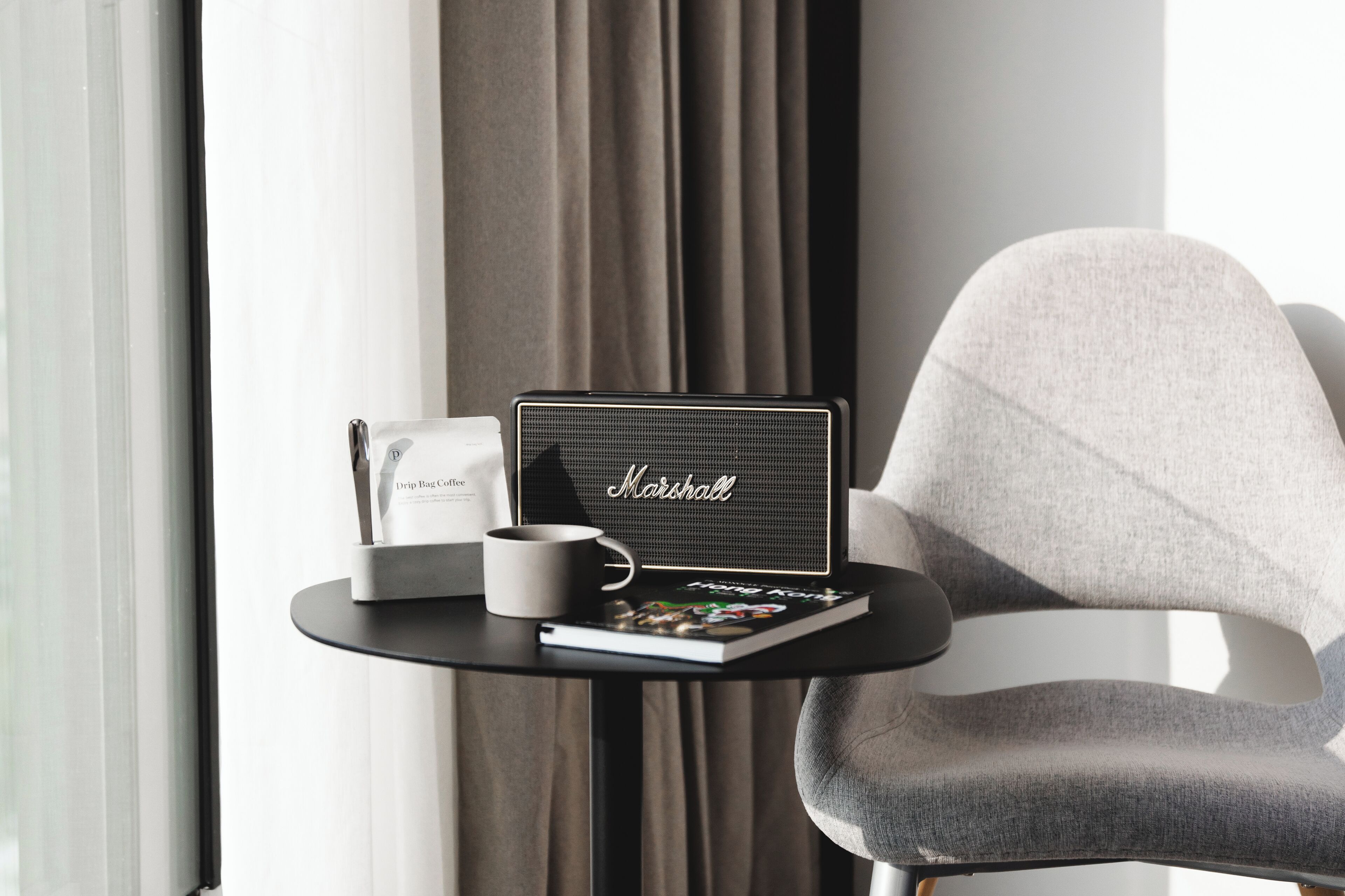 A modern hotel room with a small table featuring a laptop, a coffee mug, and a drip bag.