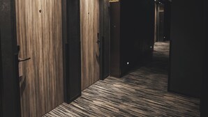 A hotel corridor with wooden doors, a patterned carpet, and recessed lighting.