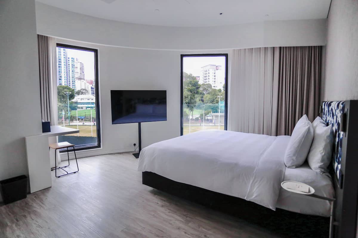 Una habitación de hotel moderna con una cama grande, un escritorio y un televisor.