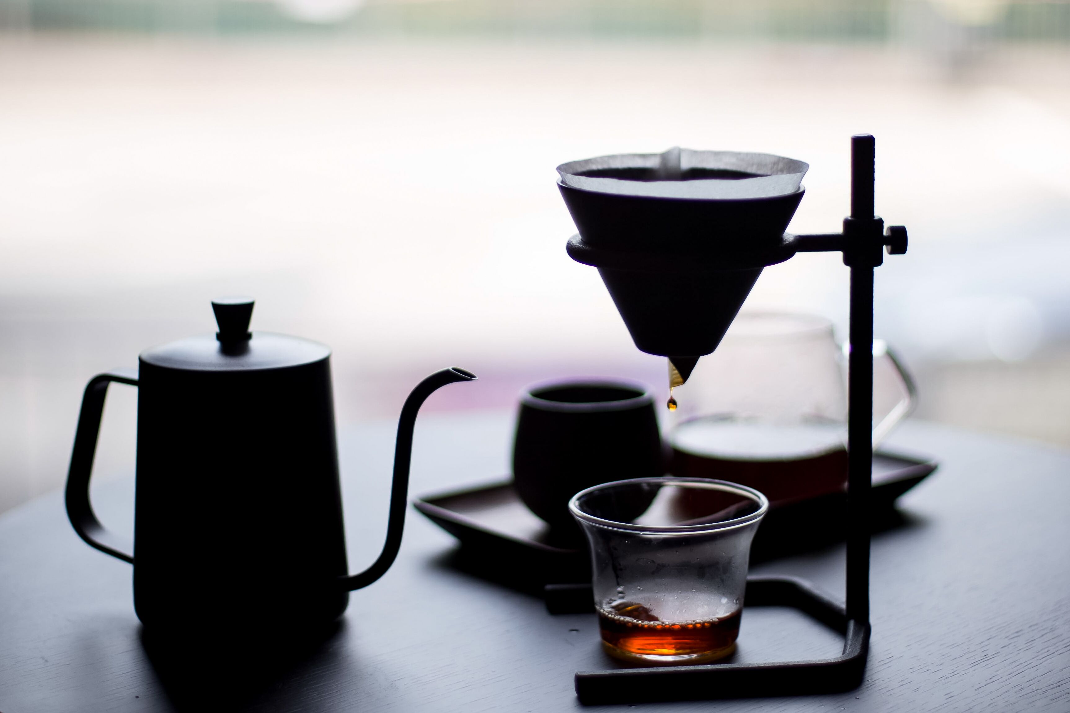 A coffee maker with a glass cup and a pot on a table.