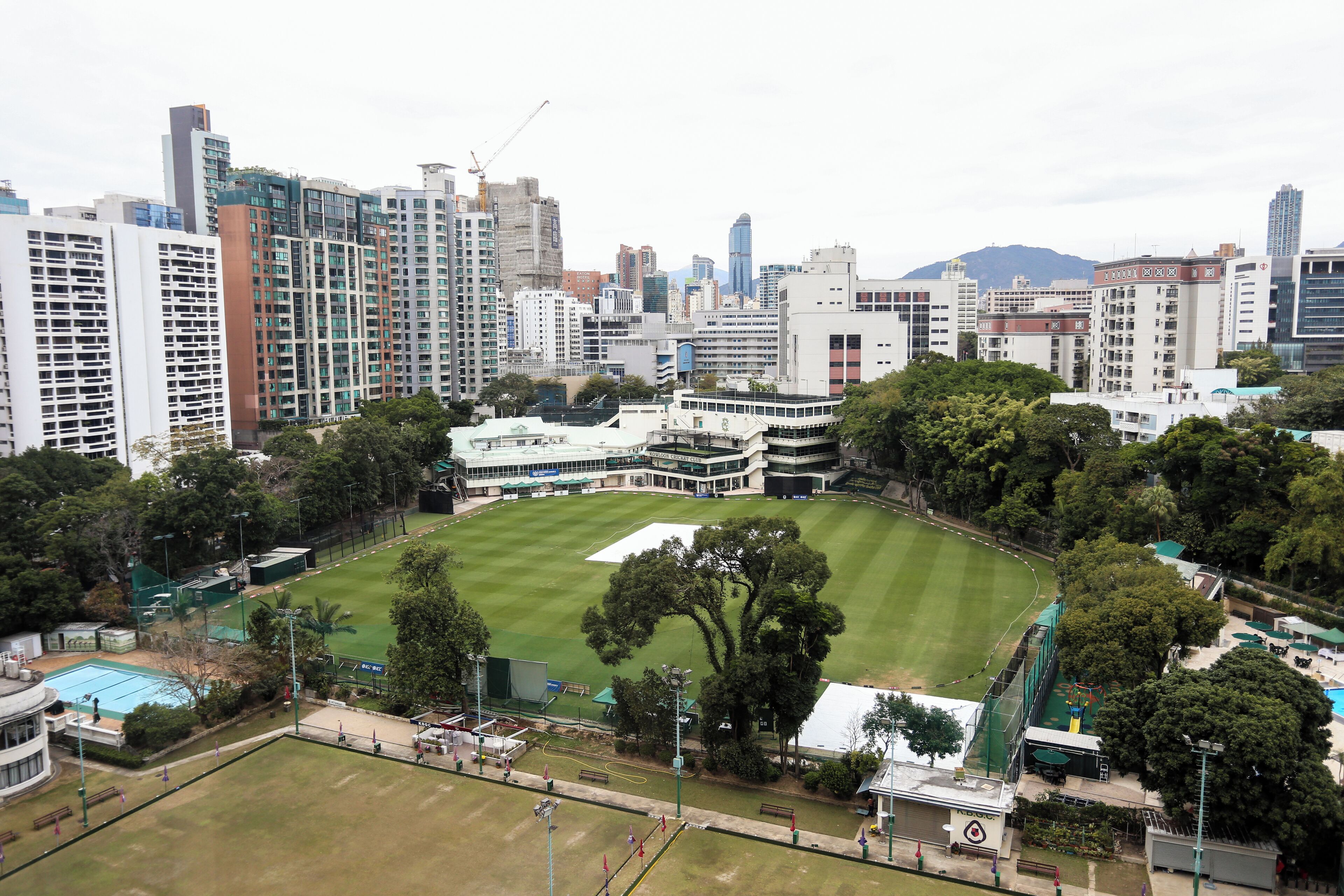 A large, open grassy area surrounded by high-rise buildings, likely a public park or sports field in an urban setting.