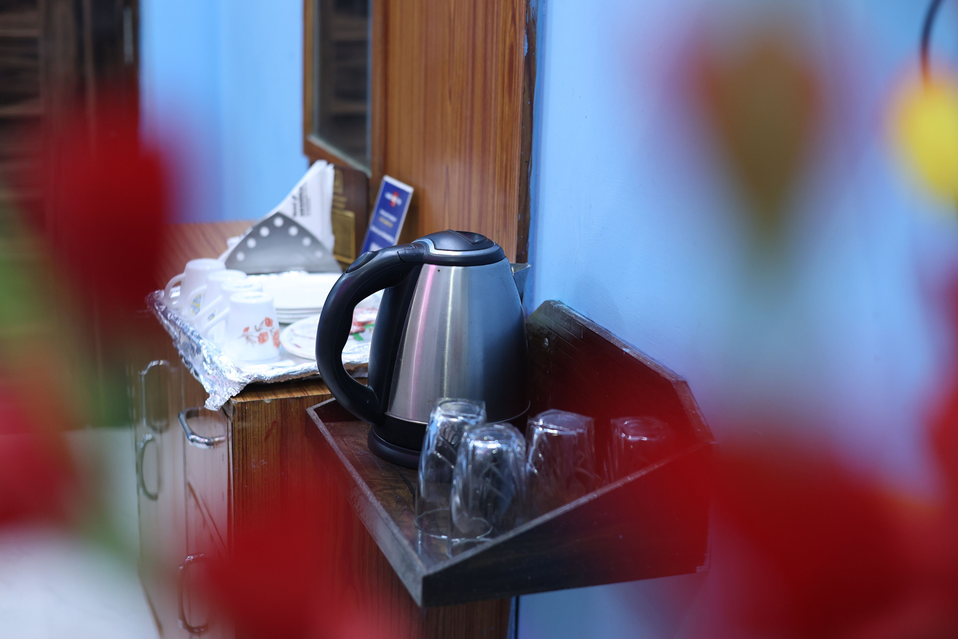 A kettle on a wooden tray with glasses and a tissue box.