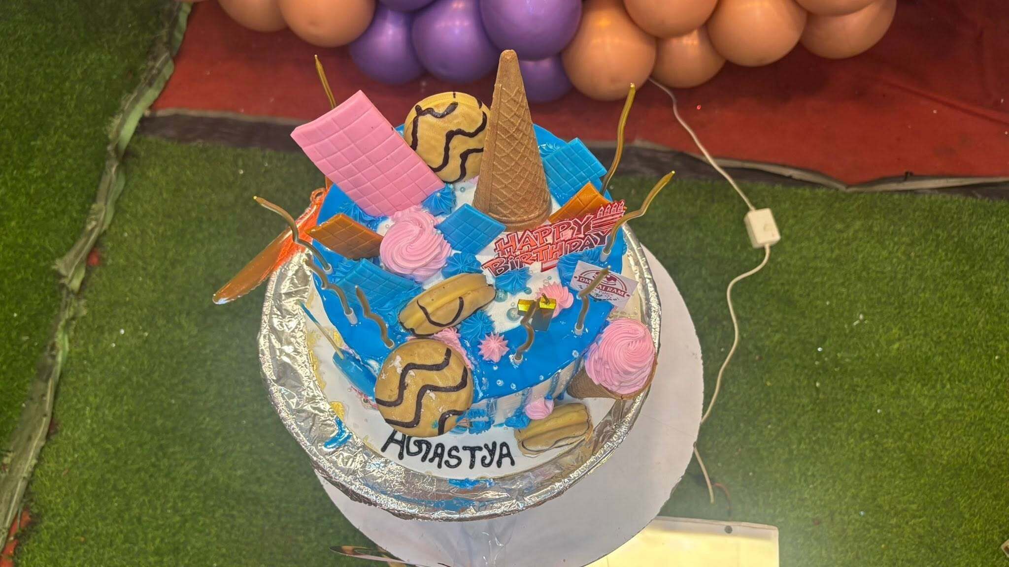 A birthday cake with various toppings and the name 'ADASTYA' on it.