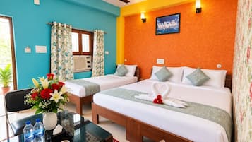 A hotel room with two beds, a desk with a chair, a vase of flowers, and a ceiling fan.