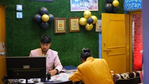 A room with a green wall, framed pictures, and a yellow door. - Hotel Anand Lok (Rajgir)