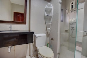 A bathroom with a toilet, sink, and glass shower enclosure. - Baan Aroonpat (Patong)