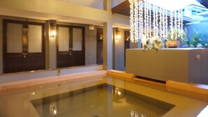 Un interior moderno con piscina de cristal, puertas de madera e iluminación decorativa.