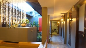 Un vestíbulo de hotel con una recepción, luces colgantes y un suelo con diseño.