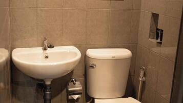 A small bathroom with a sink, toilet, and a mirror. There's a sign with instructions in a foreign language.