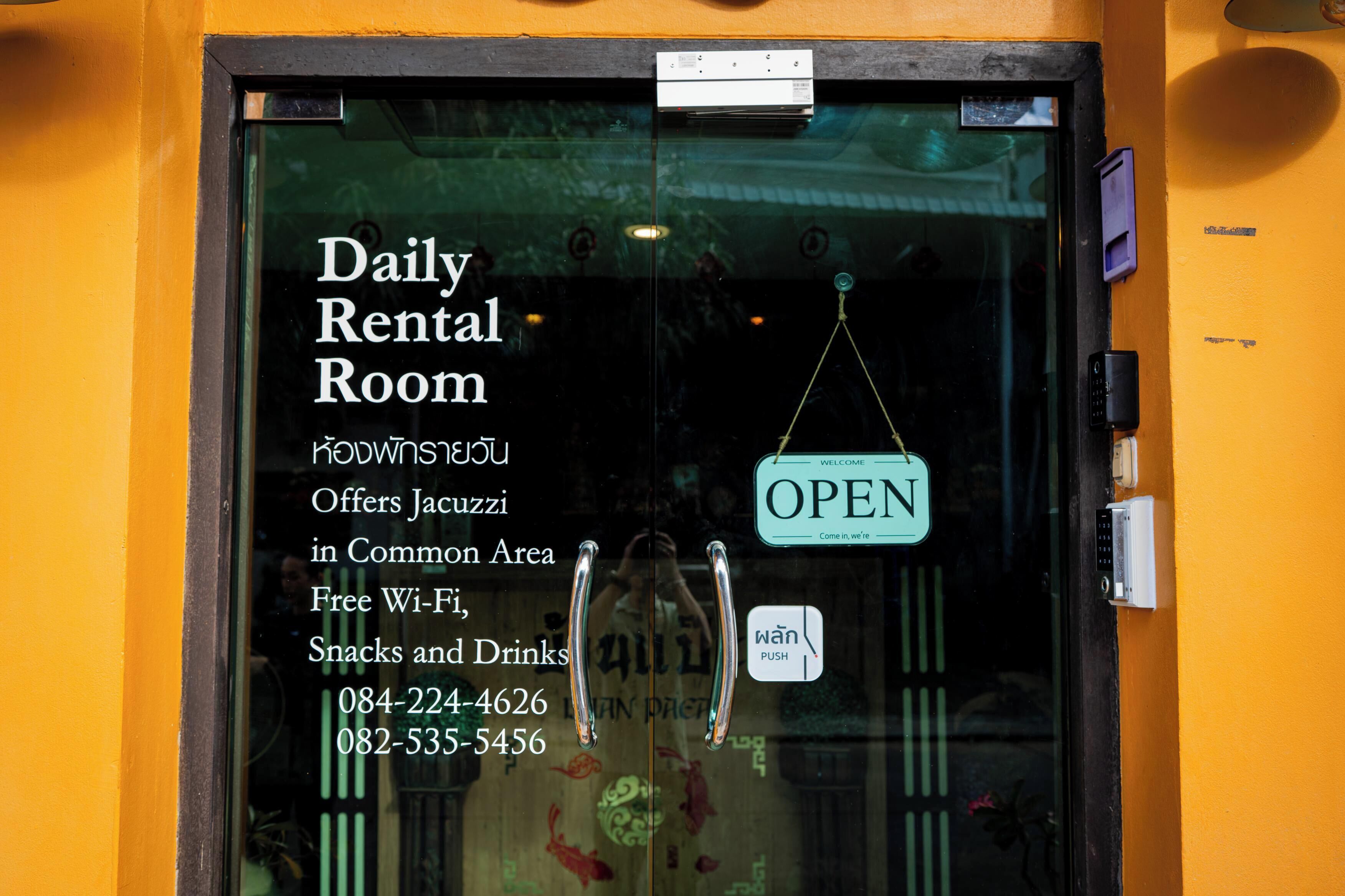 Een glazen deur met een bord dat een kamer voor daghuur aangeeft, met stekkerdozen en gratis Wi-Fi, snacks en drankjes.
