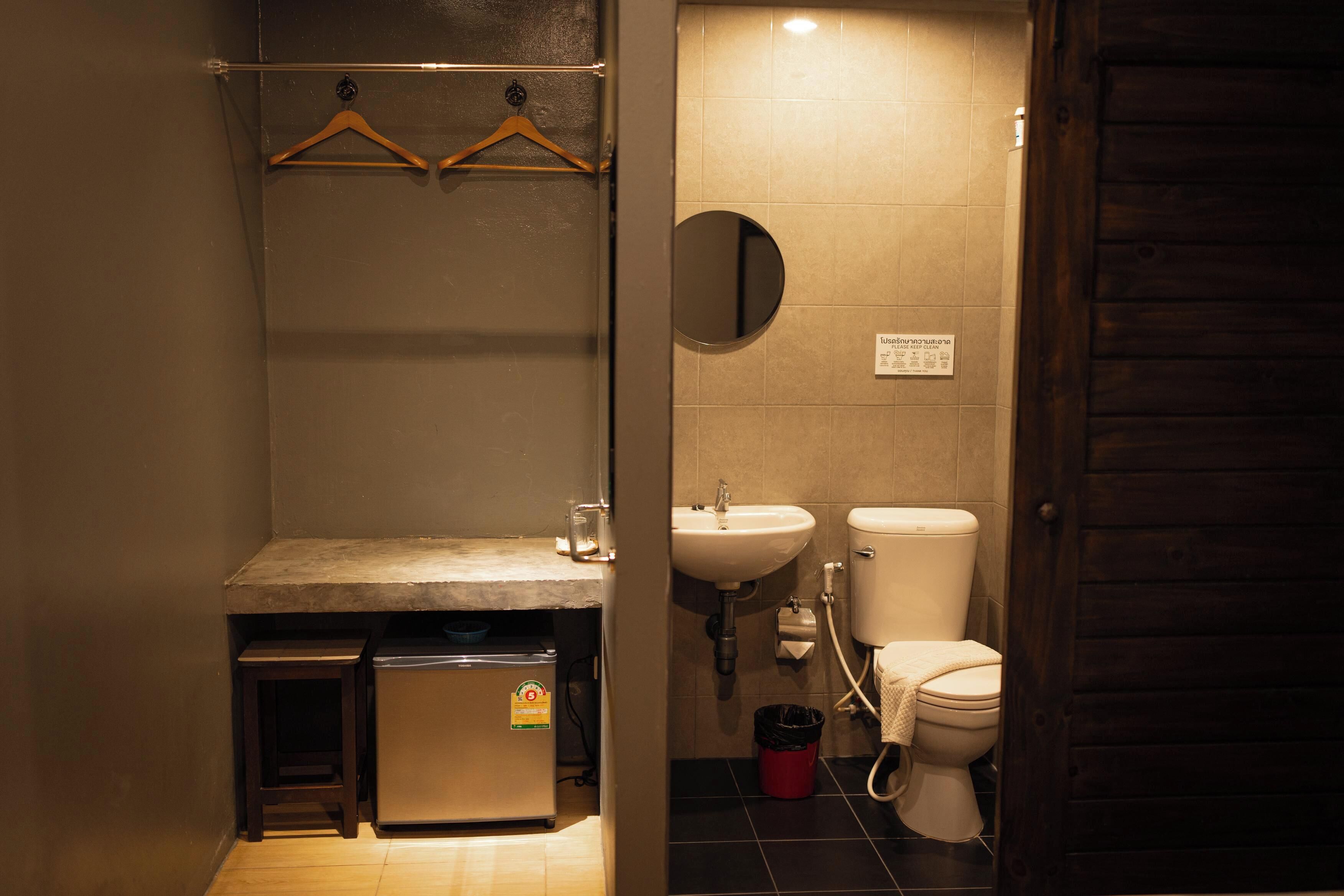 Un baño pequeño con lavamanos, inodoro y un refrigerador compacto.