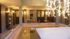 Una habitación de hotel moderna con un espejo grande, un rincón de comedor y una piscina.