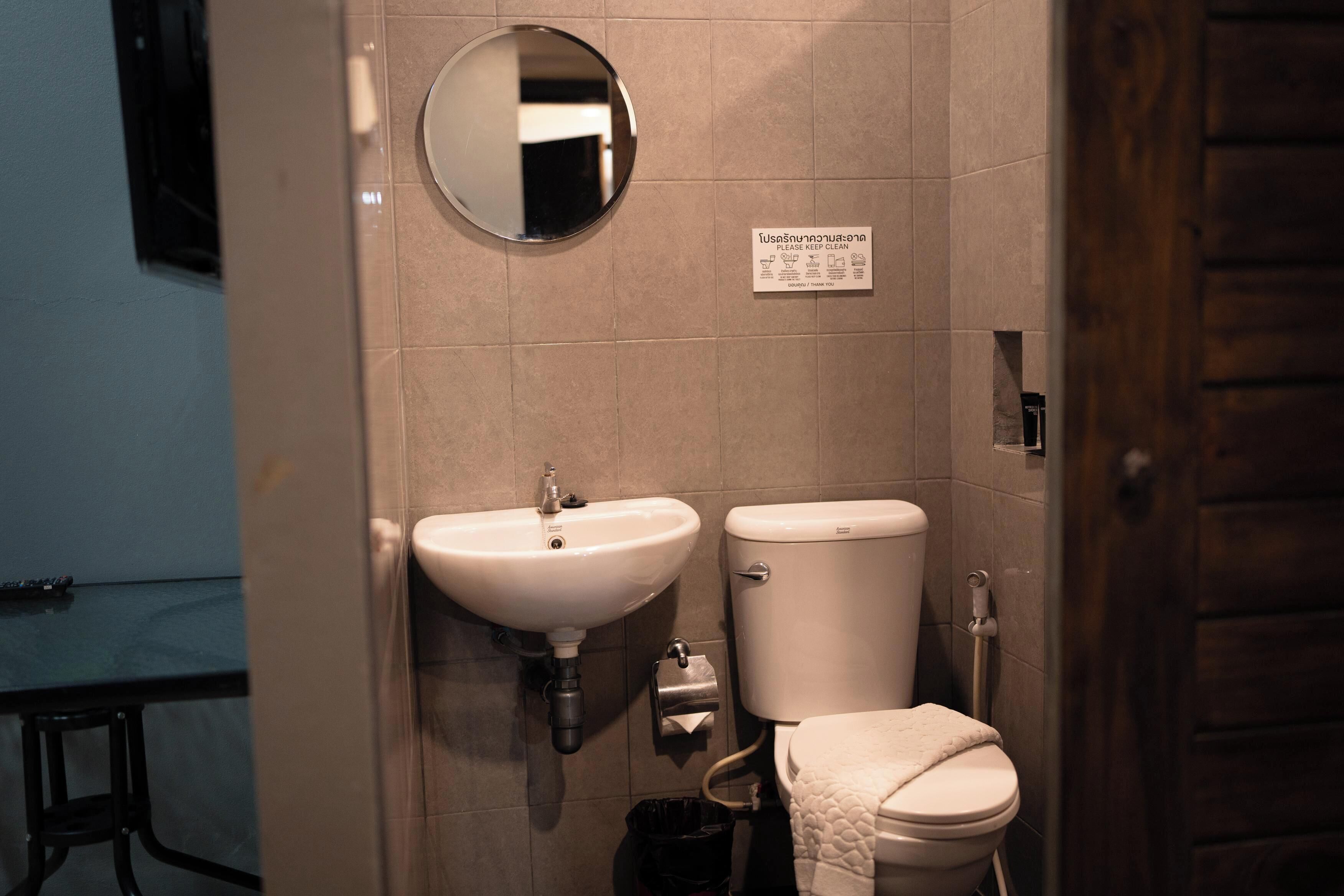 A bathroom with a white sink, a toilet, and a mirror on the wall.
