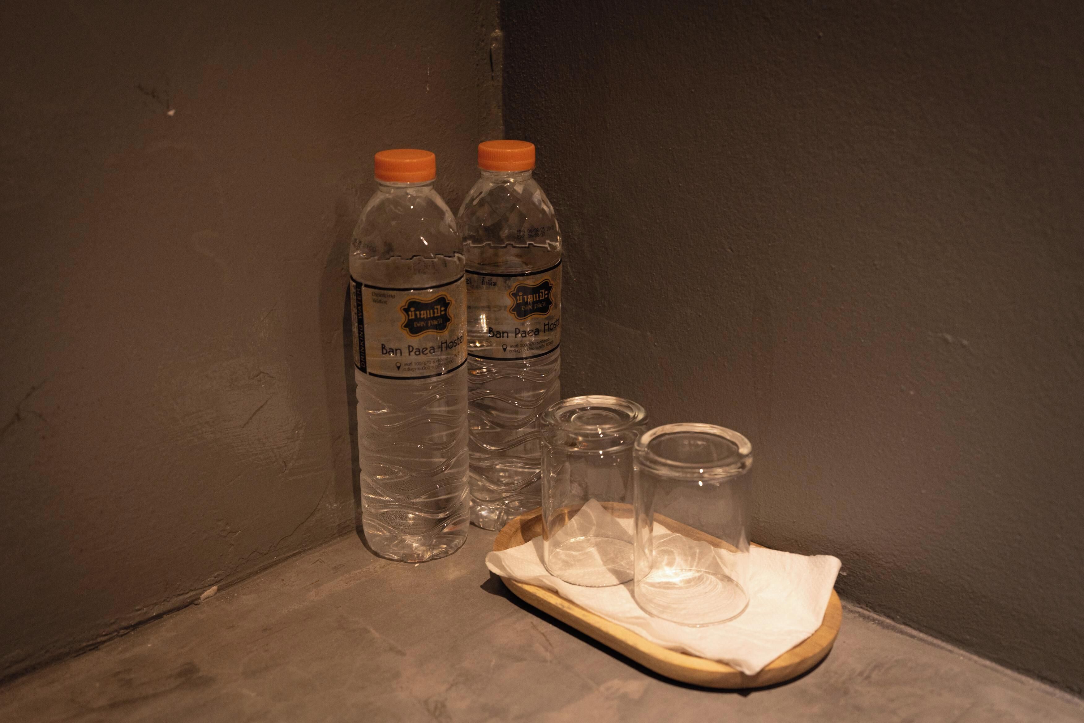 Dos botellas de agua y dos recipientes de vidrio sobre una bandeja de madera.