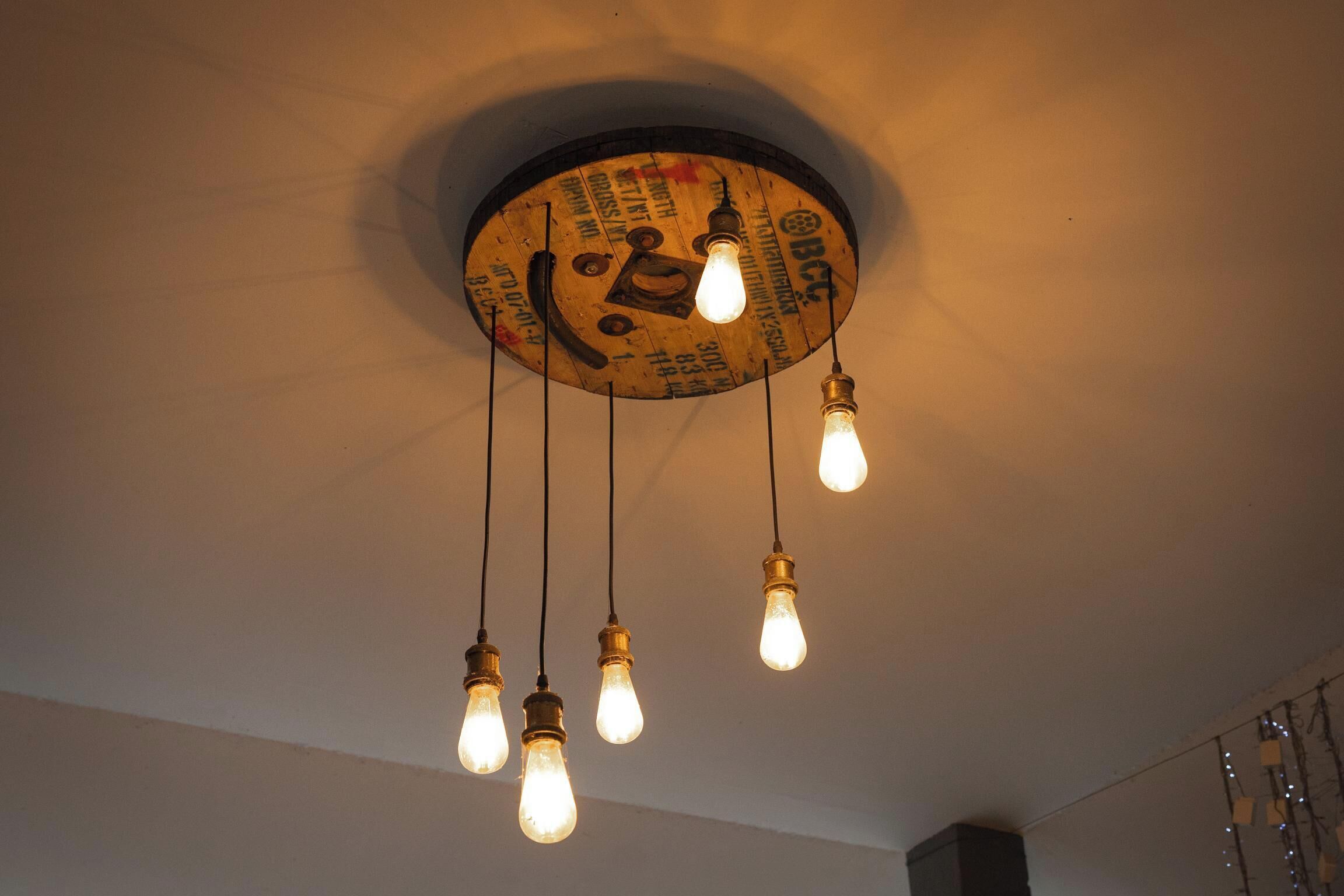 A ceiling with a circular light fixture featuring a vintage design and four hanging light bulbs.