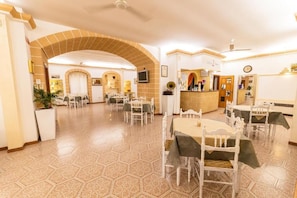 A hotel lobby with hexagonal patterned flooring, white furniture, and a reception area with a counter and a clock. - Albergo 2 Mari (Castrignano del Capo)