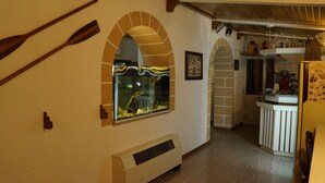 A kitchen with a built-in fish tank, a wooden spoon, and a white cabinet. - Albergo 2 Mari (Castrignano del Capo)