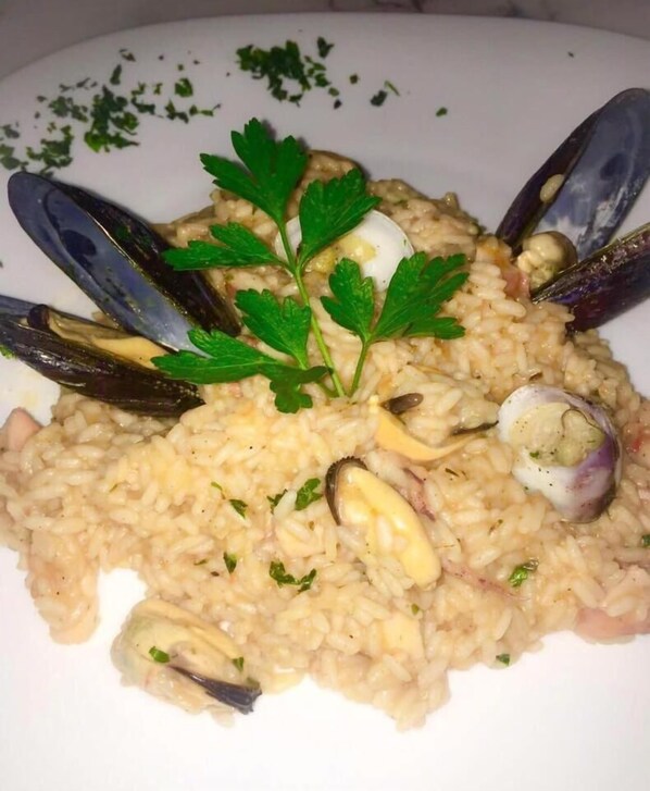 A plate of risotto with mussels and parsley garnish.
