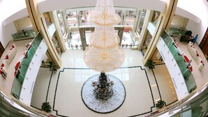 Un atrio de varios niveles con una estructura decorativa central, barandillas de vidrio y una zona de estar circular.
