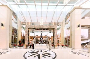 A spacious lobby with a large glass ceiling, a central Christmas tree, and a geometric floor design. - Quang Ba Trade Union Hotel (Hanoi)