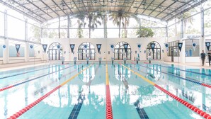 Una piscina interior con carriles delimitados, techo cubierto y puesto de socorrista.