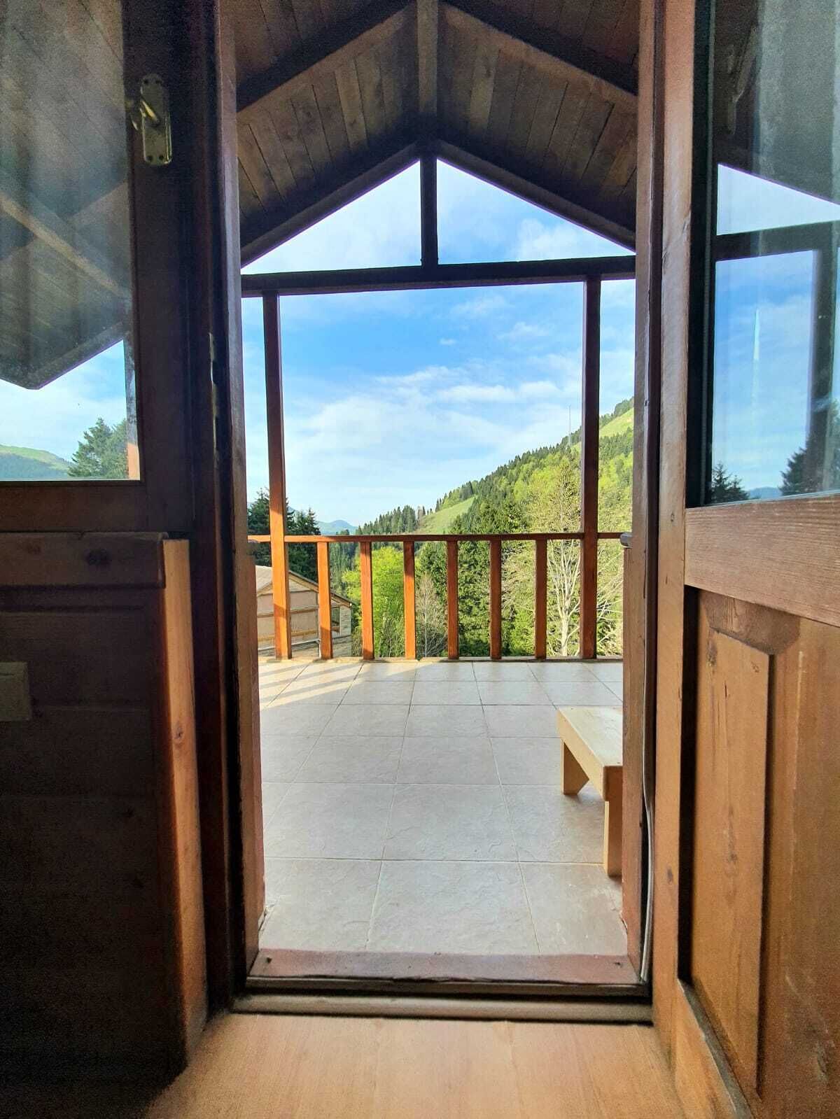 Una cabana de fusta amb un balcó que fa vedes a un vessant boscós.