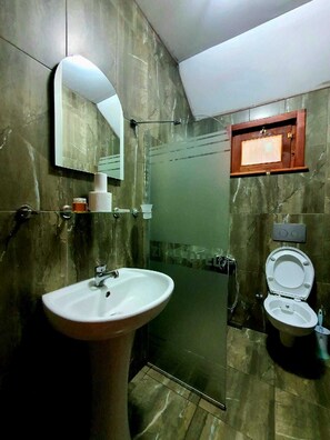 Un baño con lavamanos, inodoro y zona de ducha.
