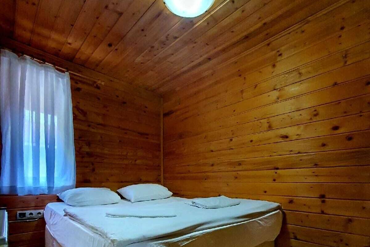 A small, cozy room with wooden walls and a single bed.