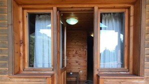 A wooden cabin with a wooden bench and a small table outside, a door leading to an interior room, and a tiled floor. - Hamsiköy Zitaş Otel & Bungalov & Restoran (Maçka)