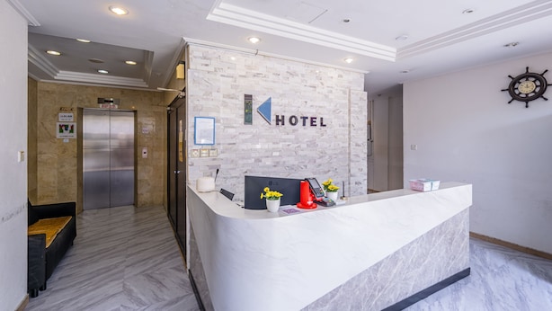 A hotel reception area with a marble counter, a clock, and a sign indicating the elevator. - K Hotel 14 (Singapore)