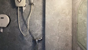 A bathroom with a handheld showerhead, a wall-mounted faucet, and a soap dispenser. - K Hotel 14 (Singapore)